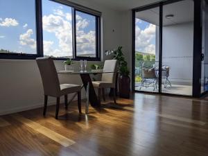 uma sala de jantar com mesa, cadeiras e janelas em The Botanical 304 em Albury