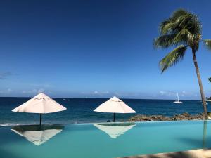 una piscina con dos sombrillas y el océano en Vacations in the Caribbean Paradise, en Sosúa