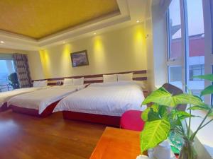 a bedroom with two beds and a table with a plant at Sen Trang Hotel in Lao Cai