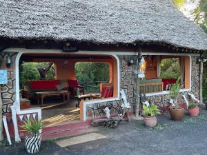 a small house with a thatch roof and a porch at Maasai Simba Camp in Amboseli