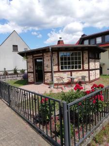 une maison avec une clôture et des fleurs devant elle dans l'établissement Ferienhaus Priepert, à Priepert