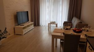 een woonkamer met een televisie en een tafel met wijnglazen bij Apartamenty Gdańsk Angielska Grobla in Gdańsk