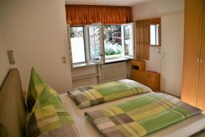 a bedroom with two beds and two windows at Haus am Bach in Bad Wörishofen