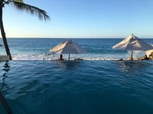 una piscina junto al océano con sombrillas en Vacations in the Caribbean Paradise, en Sosúa