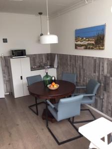 ein Esszimmer mit einem Tisch und Stühlen sowie einem Kühlschrank in der Unterkunft B&B Kogervennetje in De Koog