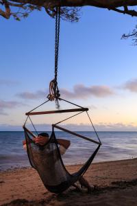 a man sitting in a hammock on the beach at Funky Fish Beach & Surf Resort in Malolo