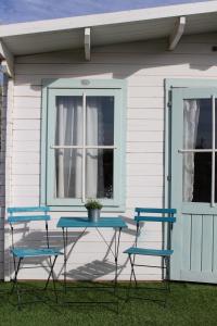 a table and three chairs in front of a house at בקתות שחר in Yonatan
