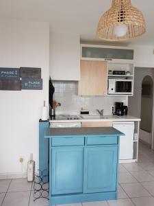 a kitchen with a blue island in the middle at Appartement T2 vue mer les pieds dans l'eau avec parking privé in Saint-Jean-de-Monts +16 photos