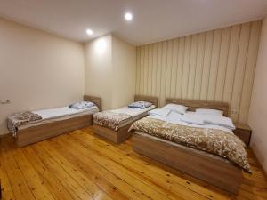 two beds in a room with wooden floors at Shorena & Nino in Kazbegi
