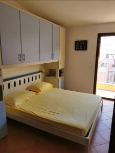 een slaapkamer met een bed met witte kasten en een raam bij Ca’ Drega in Codaruina