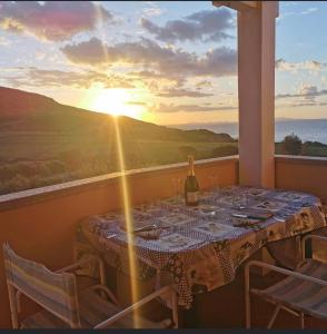 een tafel met een fles wijn op een balkon met uitzicht op de zonsondergang bij Ca’ Drega in Codaruina