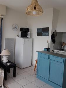 a kitchen with a white refrigerator and a table at Appartement T2 vue mer les pieds dans l'eau avec parking privé in Saint-Jean-de-Monts
