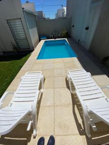 a swimming pool with two lounge chairs next to at Ventanas al Sur in San Nicolás de los Arroyos