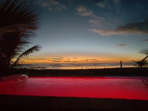 zachód słońca nad plażą z czerwonym basenem w obiekcie Alive Beach House w mieście El Tránsito