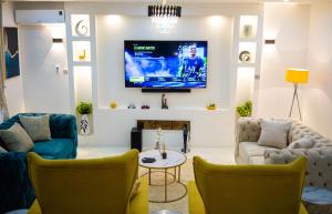 uma sala de estar com duas cadeiras e uma televisão na parede em Morak Homes - Luxury 4 bed home with PS5, 24hrs electricity, Super fast Wifi, Snooker, Games room - in a secured estate em Abuja