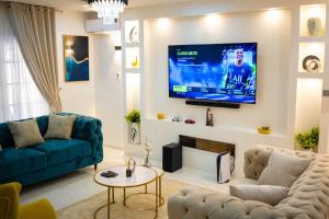 a living room with a couch and a tv on a wall at Morak Homes - Luxury 4 bed home with PS5, 24hrs electricity, Super fast Wifi, Snooker, Games room - in a secured estate in Abuja