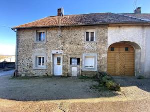 a stone house with a garage and a door at Un cocon en plein coeur du Jura - Chatillon in Châtillon