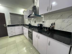 a kitchen with white cabinets and black counter tops at Morak Homes - Luxury 4 bed home with PS5, 24hrs electricity, Super fast Wifi, Snooker, Games room - in a secured estate in Abuja