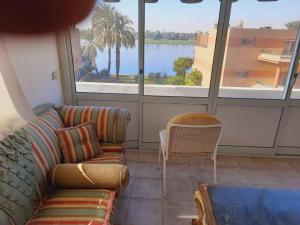 - un salon avec un canapé et une grande fenêtre dans l'établissement Nile Horizon apartments, à Jazīrat al ‘Awwāmīyah