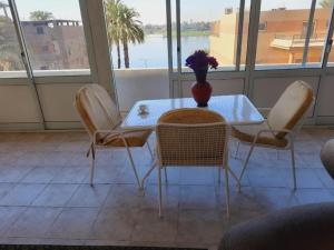 una mesa y sillas con un jarrón encima en Nile Horizon apartments, en Jazīrat al ‘Awwāmīyah