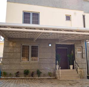 a house with awning over the front of it at Morak Homes - Luxury 4 bed home with PS5, 24hrs electricity, Super fast Wifi, Snooker, Games room - in a secured estate in Abuja