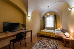 Pokój z łóżkiem i biurkiem z telewizorem w obiekcie Apartmany Kolegium w Preszowie