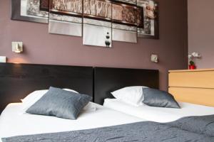Schlafzimmer mit einem Bett mit weißer Bettwäsche und blauen Kissen in der Unterkunft Hôtel Les Flots Bleus in Savines