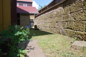 un muro di mattoni accanto a un cortile con un edificio di FH Am Osterbrunnen a Hinterhermsdorf