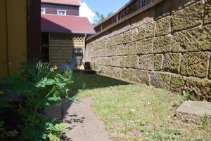 a brick wall next to a yard with a building at FH Am Osterbrunnen in Hinterhermsdorf