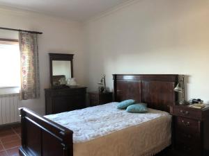 a bedroom with a bed with a wooden headboard and a mirror at Quinta das Oliveiras in Moimenta da Serra