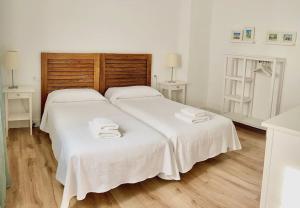 - une chambre avec 2 lits, des draps blancs et des serviettes dans l'établissement Moderno apartamento en San Bartolomé, à Séville