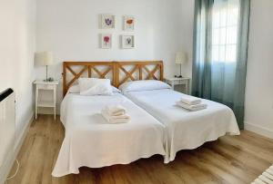 - une chambre avec un grand lit blanc et des serviettes dans l'établissement Moderno apartamento en San Bartolomé, à Séville
