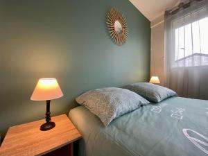 カルカソンヌにあるL'Appartement Jebari - Esprit loft Carcassonne proche cité médiéval et aéroportのベッドとランプ付きのテーブルがある寝室