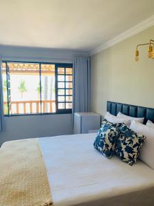 1 dormitorio con 1 cama grande y ventana en Suíte frente mar e pés na areia, en Japaratinga