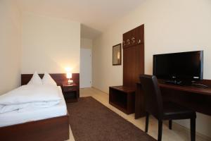 a hotel room with a bed and a desk with a television at Hügellandhof in Premstätten bei Vasoldsberg