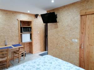 a room with a bed and a desk and a television at Couettes et Picotin in Durbuy