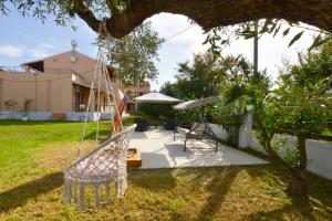 a swing in a yard with a table and an umbrella at Kalliopi Apartments in Roda