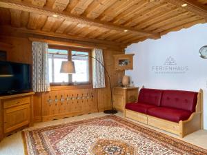 sala de estar con sofá rojo y ventana en Ferienwohnung an der Familienabfahrt, en Brixen im Thale