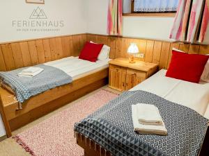 two beds in a small room with red pillows at Gartenwohnung an der Familienabfahrt in Brixen im Thale