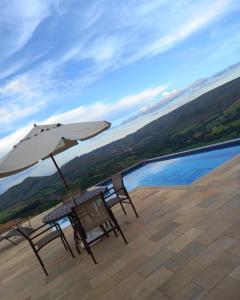 two chairs and an umbrella on a patio with a view at Chácara Sossego in Capitólio