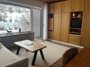 ein Wohnzimmer mit einem Tisch und einem großen Fenster in der Unterkunft Cozy Condo, Ski in and Out in Todtnau