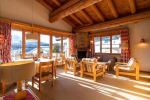 a living room with a table and chairs and windows at Edelweiss Darblauna Sut in Flims