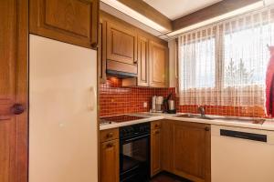 - une cuisine avec des placards en bois et un réfrigérateur blanc dans l'établissement Edelweiss Darblauna Sut, à Flims