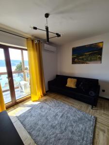 sala de estar con sofá negro y cortina amarilla en Apartament Lake View z sauną i widokiem na jezioro en Kluszkowce