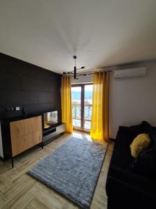 salon z żółtymi zasłonami i kanapą w obiekcie Apartament Lake View z sauną i widokiem na jezioro w Kluszkowcach