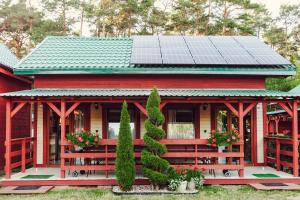 a red house with a solar roof with flowers at Domki Leśny Zakątek in Pogorzelica