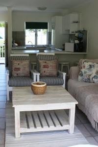 a living room with a coffee table and a kitchen at Riverclub Villas in Plettenberg Bay