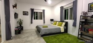Swiss Bungalow Cha Am في تشا أم: غرفة نوم بسرير ومخدات خضراء