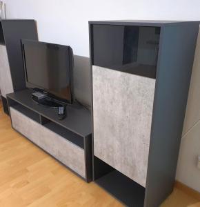 a black entertainment center with a flat screen tv at Private Bed in a Shared Spacious Apartment in St. Gallen