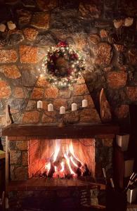 a stone fireplace with a christmas wreath and candles at Chalet D'elite in Palaios Agios Athanasios